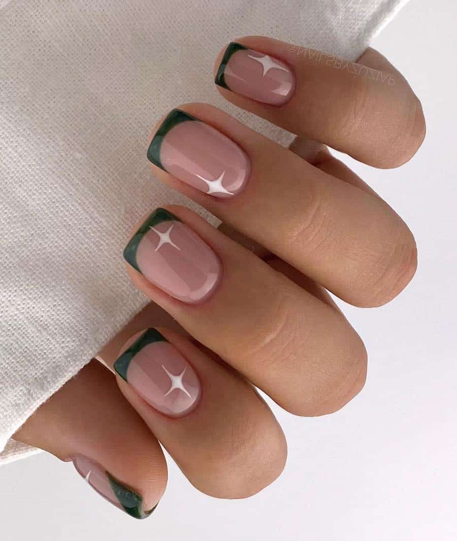 a hand with short square nude nails with forest green French tips and white sparkle accents
