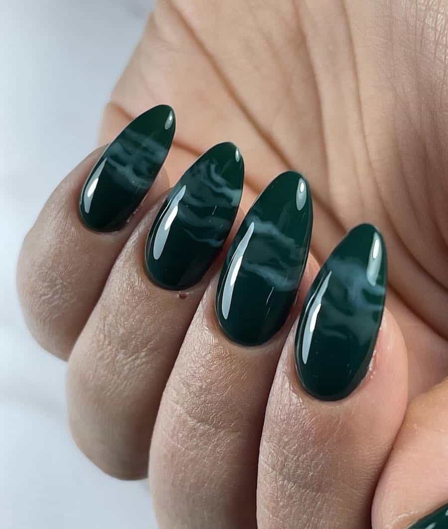 a hand with long forest green almond nails with white marbling
